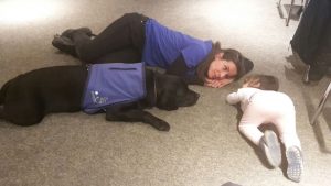 Corso, la perra de terapia y la niña tumbadas en el suelo
