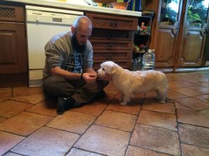 Educador canino dando de comer con la mano derecha a su perra Ayni